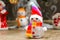 The snowman in a cap and a striped scarf costs on a floor near a fir-tree against the background of other snowmen and Father Frost