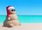 Snowman in Christmas Santa hat and sunglasses at sea beach