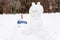 Snowman in the form of cat standing on the background of white snowdrifts in the winter landscape.