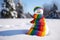 Snowman with the lgbt rainbow colors in a winter Christmas scene with snow, pine trees and warm light. Merry Christmas background