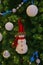 Snowman little soft toy with shining balls ornament hanging on green christmas tree background