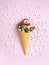 Snowman, marshmallows, Christmas tree twigs and lollipops in a waffle cone. Pink background. An original sweet gift