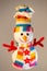 Snowman plush with a multicolored scarf and hat, with two buttons in the shape of a star and arms in the shape of a red branch