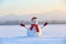 Snowman in red hat and scarf. Christmas scenery. High mountains at the background.