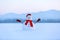 Snowman in red hat and scarf. Christmas scenery. High mountains at the background. Ground covered by snow.