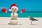 Snowman. Sandy Snowman on the beach. Christmas snowman with red Santa Claus hat and mittens. Smiley Snow man