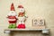 snowman and santa toys on a shelf, wooden calendar with 25 december date, christmas banner, copy space for promo or ad