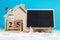 Snowman sitting on wooden block calendar set on 25 December beside blackboard on white wool in front of Wooden house. Copy space f