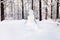 snowman on snowy meadow in forest park in winter