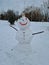 A snowman stands in the park. The smiling Snowman
