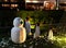 A snowman and three evil penguins are standing on a green lawn. Snowman with a green nose. Christmas celebration in countries with