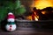 Snowman under a Christmas tree near a burning fireplace, close-up, Christmas composition