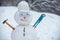 Snowman worker on snow background. Funny snowman in work helmet on snowy field. Handmade snowman in the snow outdoor.