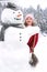 Snowman and a young girl outside in snowfall