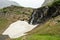 Snowmelt Drops Over Cliff Wall and Under Snow Field