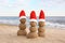 Snowmen made of sand with Santa hats near sea. Christmas vacation