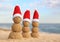 Snowmen made of sand with Santa hats near sea. Christmas vacation