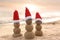 Snowmen made of sand with Santa hats near sea at sunset. Christmas vacation