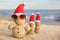 Snowmen made of sand with Santa hats and sunglasses on beach. Christmas vacation