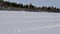 Snowmobile drives along vast snowy valley crossed by tracks