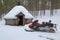 Snowmobile in front of Finnish Kota in a snow-covered landscape.