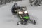 Snowmobile at high speed while it is snowing in the pine forest