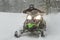 Snowmobile at high speed while it is snowing in the pine forest