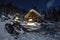 Snowmobile from house chalets in winter forest with snow in light moon and starry sky