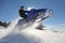 Snowmobile rider jumping through powder