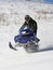 Snowmobile rider racing through powder