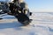 A snowmobile stands on the snow at sunset.