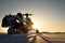 A snowmobile stands on the snow at sunset.