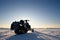 A snowmobile stands on the snow at sunset.