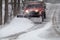 Snowplow in action clearing residential roads during snow storm