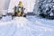 Snowplow plowing road during storm. Winter snow removal yellow large tractor