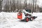 A snowplow removes snow on the road in the park.