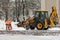 Snowplow and workmen with shovels at work in winter