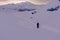 Snowshoe hiking at dawn through winter landscape along path towards sunrise behind mountains