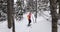 Snowshoeing people in winter forest with snow covered trees on snowy day. Woman on hike in snow hiking in snowshoes