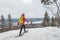 Snowshoeing people in winter forest with snow covered trees on snowy day. Woman on hike in snow hiking in snowshoes