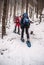 Snowshoeing tourists on winter hiking trail in forest in Fischbacher Alpen