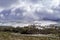 Snowstorm sky landscape over countryside and snowy trees. Dirt road to the mountain