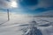 Snowstorm in the valley during sunny day and road is full of snow and electric poles with broken wires.