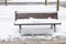 Snowy bench in winter covered with snow in a frosty December and cold winter from January to February with blizzards and snowfall