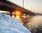 Snowy bridge and beautiful frosty sunset on the river in winter