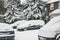 Snowy cars and firn trees near a house