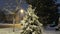 Snowy city park in light of lanterns at evening. Snow-covered trees and benches, footpath in a fabulous winter night park. Winter