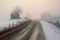 snowy country road disappearing into the foggy horizon