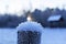 Snowy crystal cap on a wooden cut and the setting sun at sunset against the background of a gazebo by lake and forest