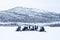 Snowy day with people riding the snowmobiles and a mountain in the distance in the north of Sweden